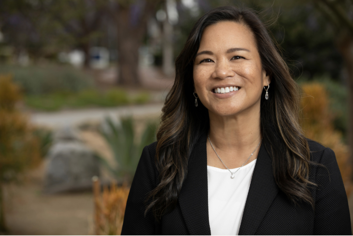 Asian woman smiling with brown hair parted on the side.