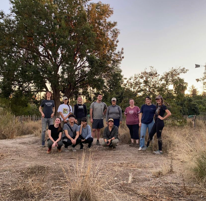 students in a meadowposing for a picture while smiling.