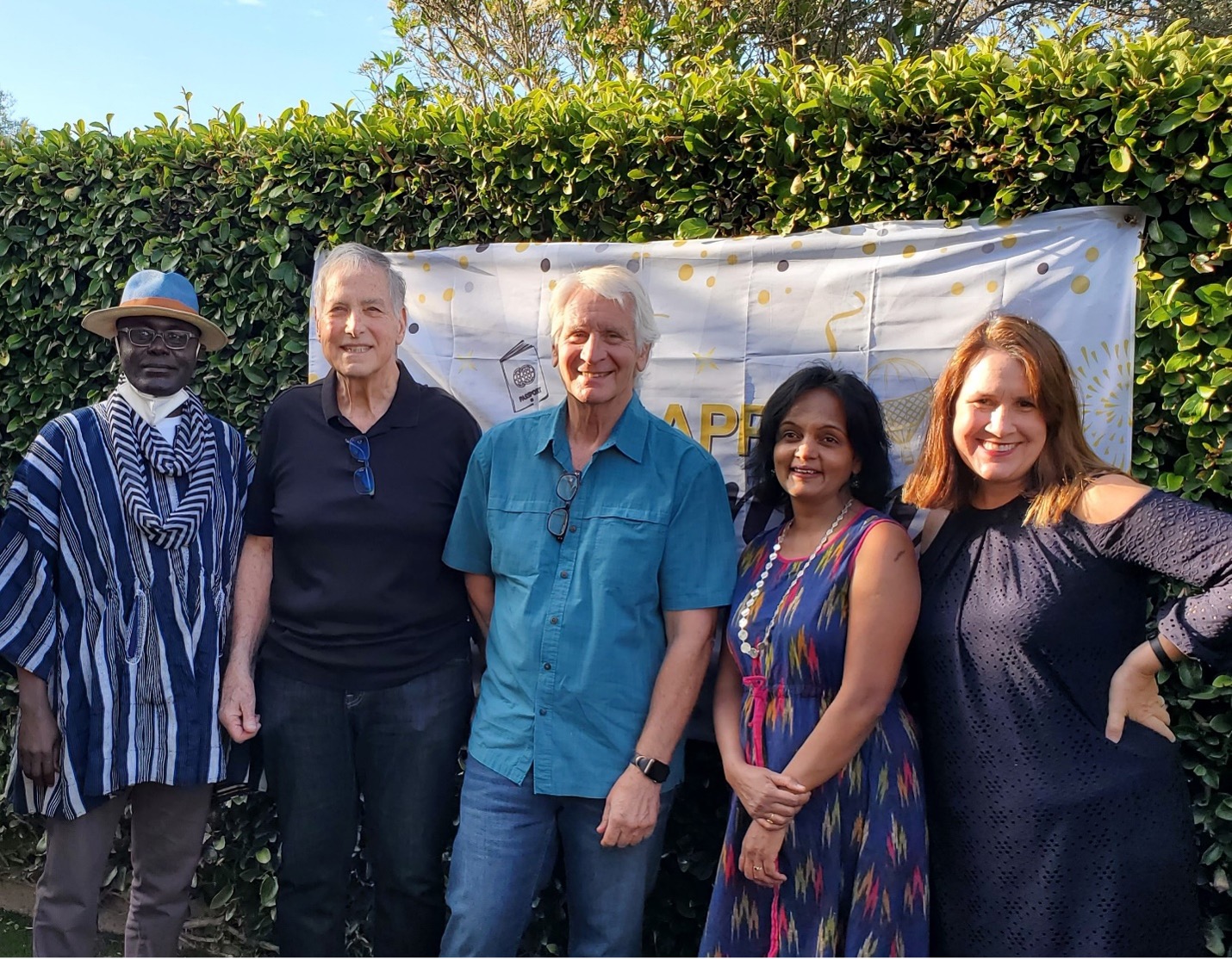 Faculty and staff smiling and posing for a picture on a warm evening.