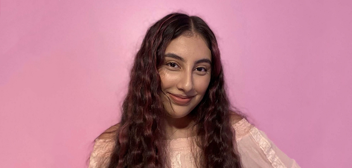 Brown student with curly hair and pink background